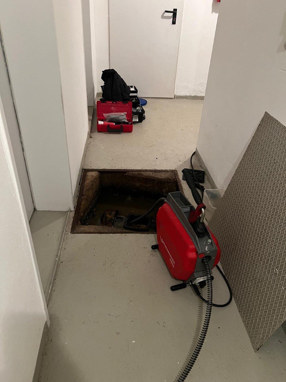 Rohrreinigungsmaschine an einem geöffneten Zugang zur Abwasserleitung